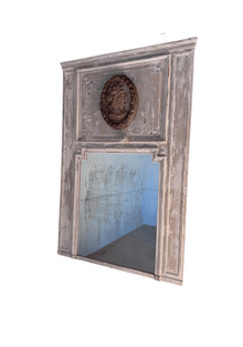 1800s French trumeau mirror in original weathered gray paint, with a carved oval profile medallion above a foxed mirror plate