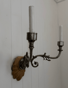 Close-up of hand-forged scrolling iron arm and carved shell backplate on antique Sheffield sconce