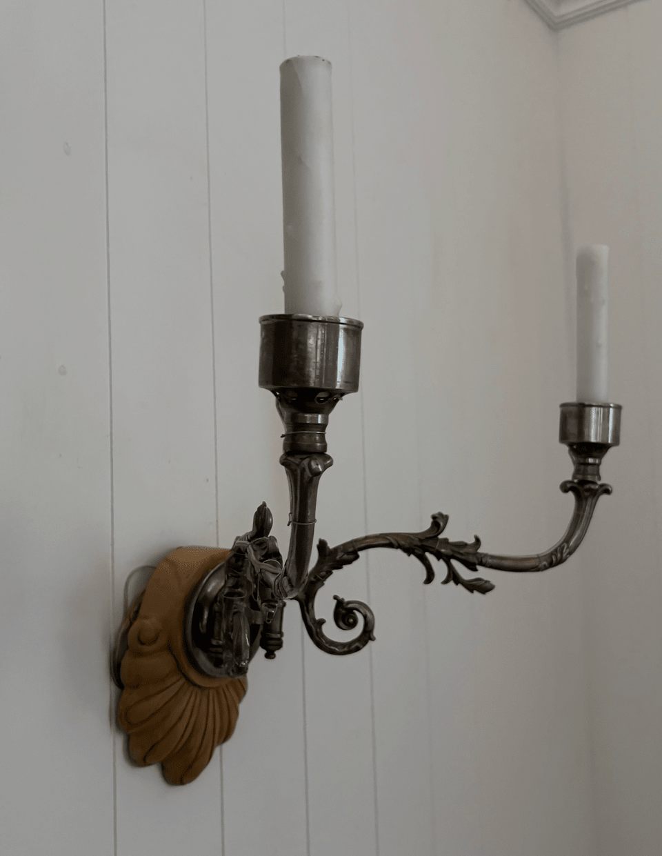 Close-up of hand-forged scrolling iron arm and carved shell backplate on antique Sheffield sconce