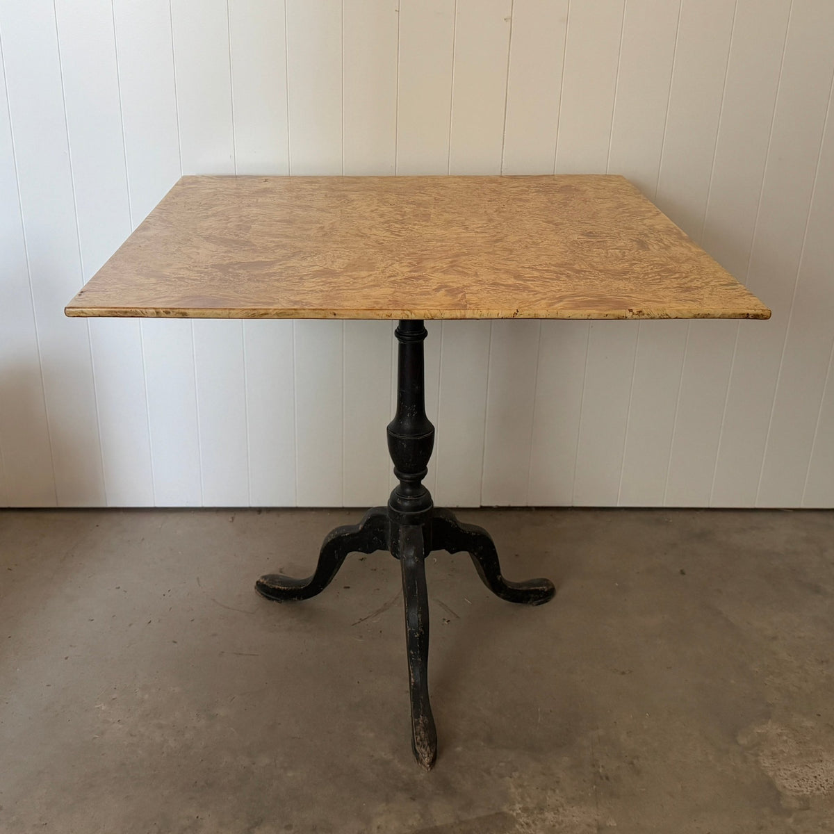 Bleached burl wood tilt-top table shown at an angle with the tabletop tilted up