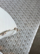 Close-up of the striped floral cushion fabric on the daybed with the corner of a linen pillow visible
