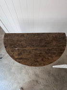 Overhead view of the half-round dark stained tabletop, showing plank seams and worn, mottled wood grain