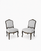 Pair of ebonized Louis XV-style side chairs with gilt floral accents, cabriole legs, and gray striped upholstery, shown on a white background