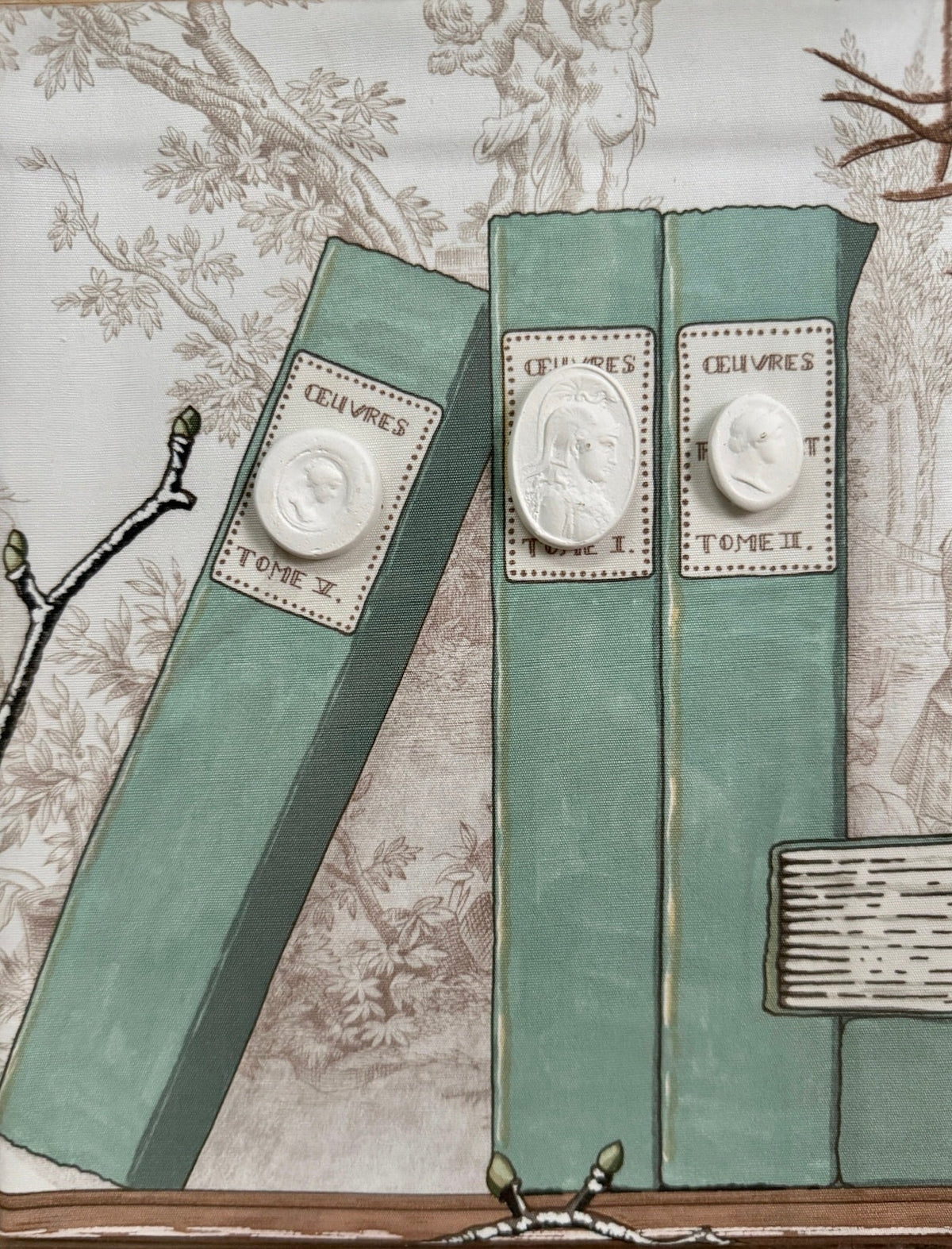 Close-up of the painted green book spines with white cameo medallions in the shadowbox