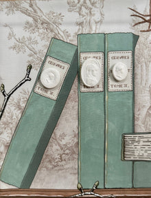 Close-up of the painted green book spines with white cameo medallions in the shadowbox