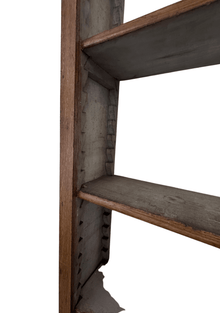 Close-up of the bookcase's interior side rail showing the notched shelf-support pins and gray-toned faux bois graining