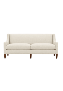 Quick Ship Kenilworth sofa with slope arms, two seat cushions, and tapered wood legs, upholstered in cream fabric, against a white background.